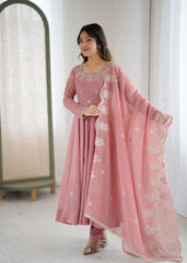 Woman wearing a pink traditional outfit with embroidery in a minimalistic room.