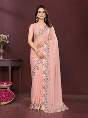 Woman wearing a pink saree with floral patterns against a dark background