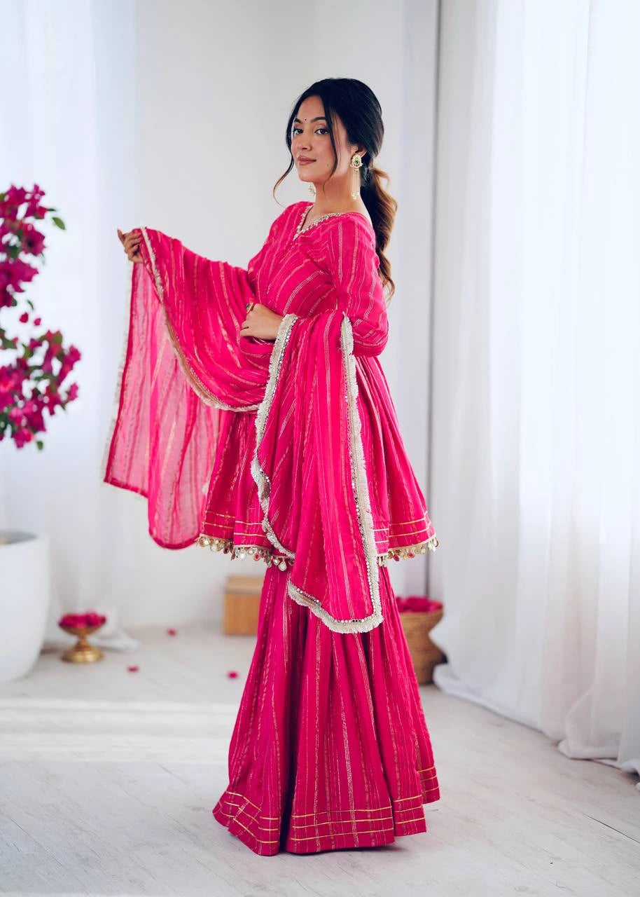 Woman in a bright pink saree with white border indoors