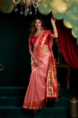 Woman in a pink saree with red blouse standing in a decorated room.