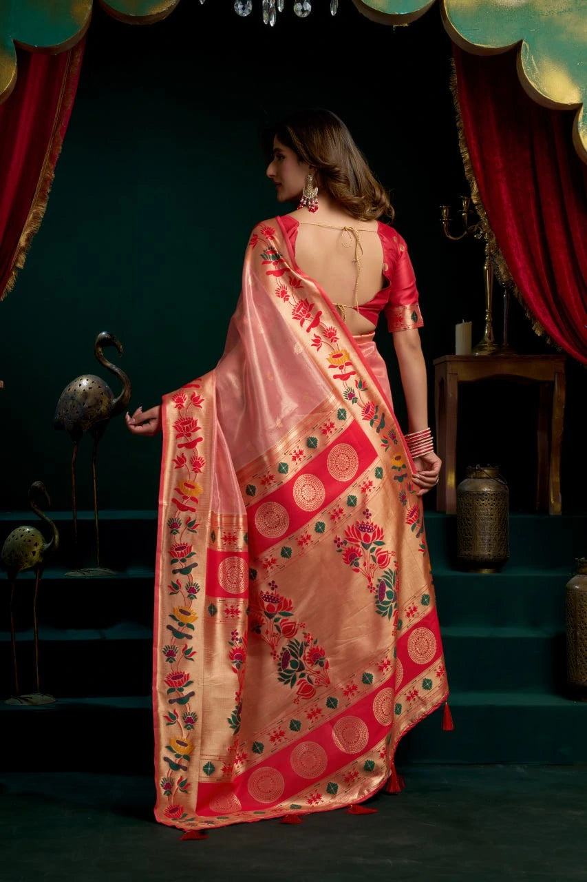 Woman in a traditional pink saree with floral patterns in a decorative setting.