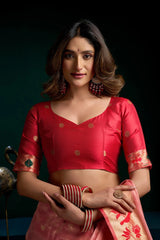 Woman wearing a red blouse with gold patterns and a pink saree against a dark background