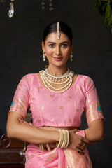 Woman in a pink saree with jewelry against a dark background