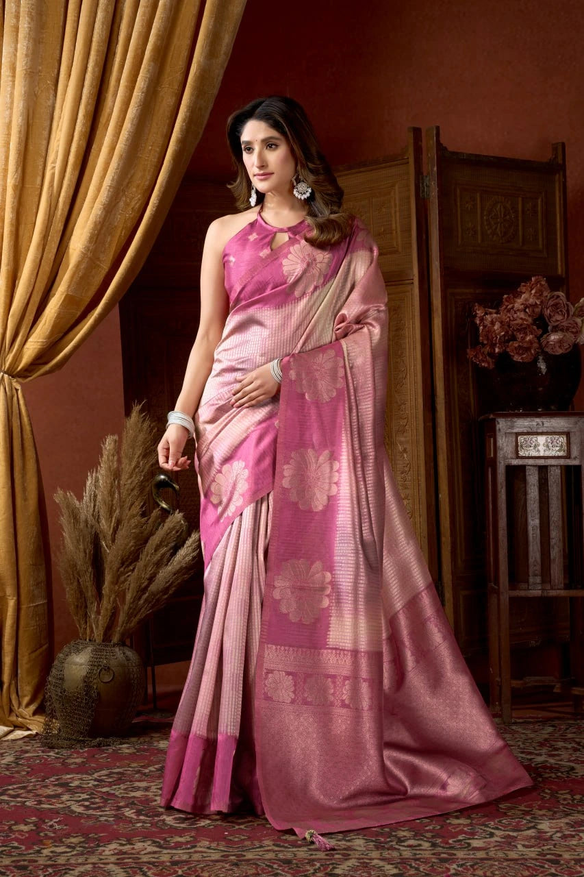Woman in a pink saree standing in a room with decorative elements.