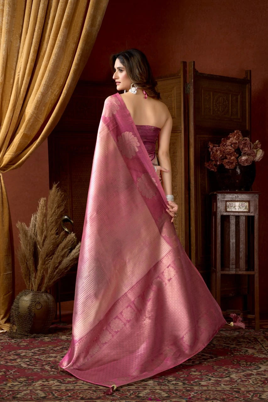 Woman in a pink saree standing in a room with a warm ambiance
