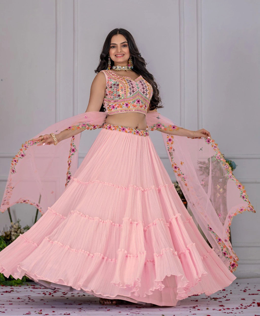 Woman in a pink traditional outfit with floral details against a white background