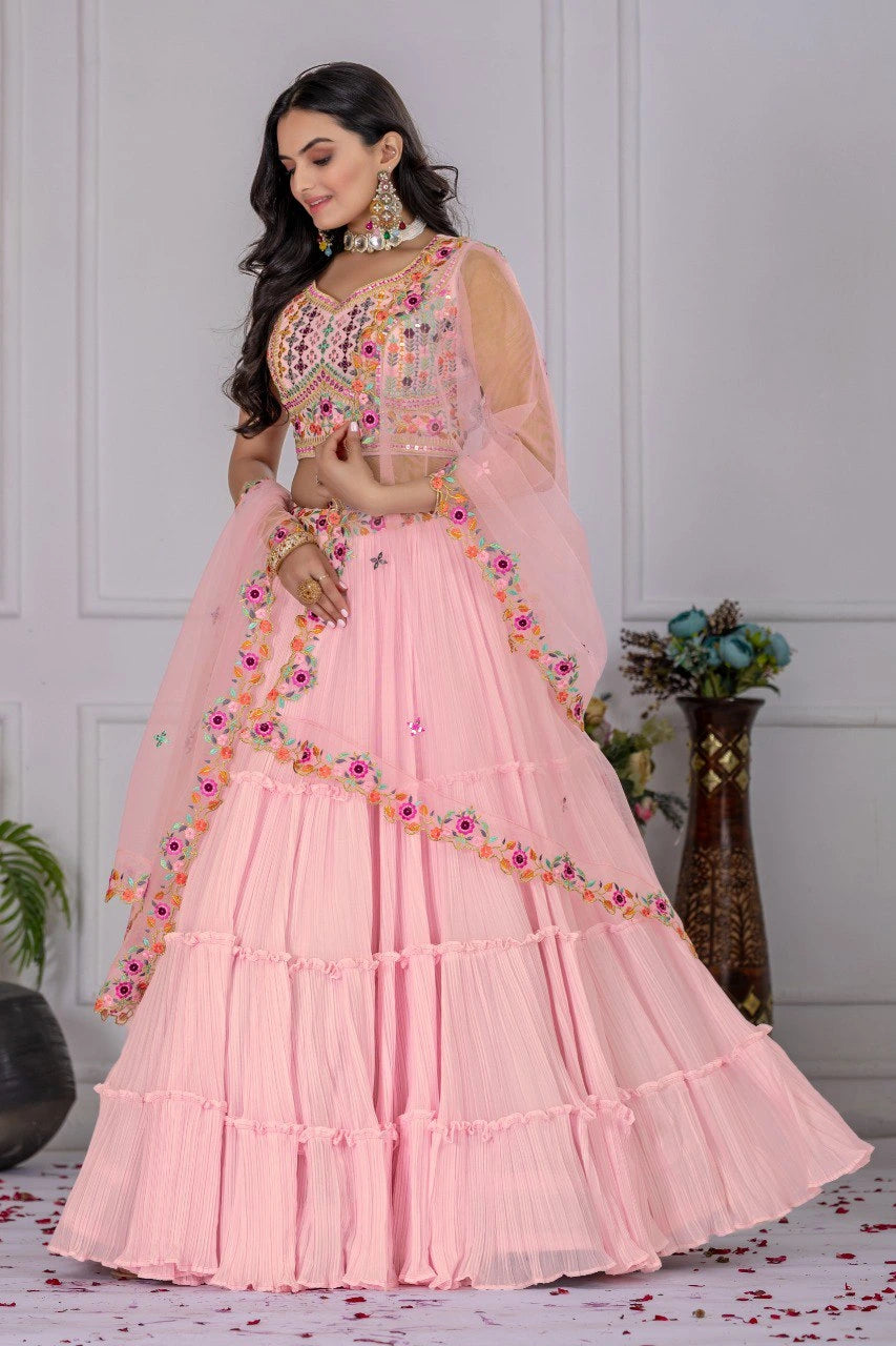 Woman in a pink traditional outfit with floral embellishments in an indoor setting.