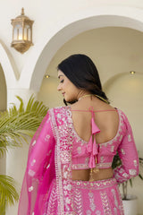 Woman wearing a pink embroidered traditional outfit with a white background