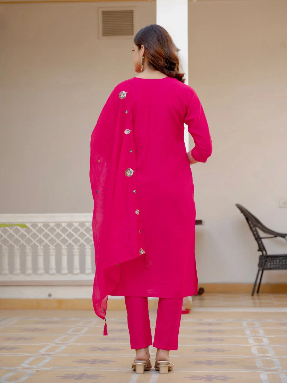 Woman wearing a bright pink traditional outfit with a dupatta in an indoor setting.