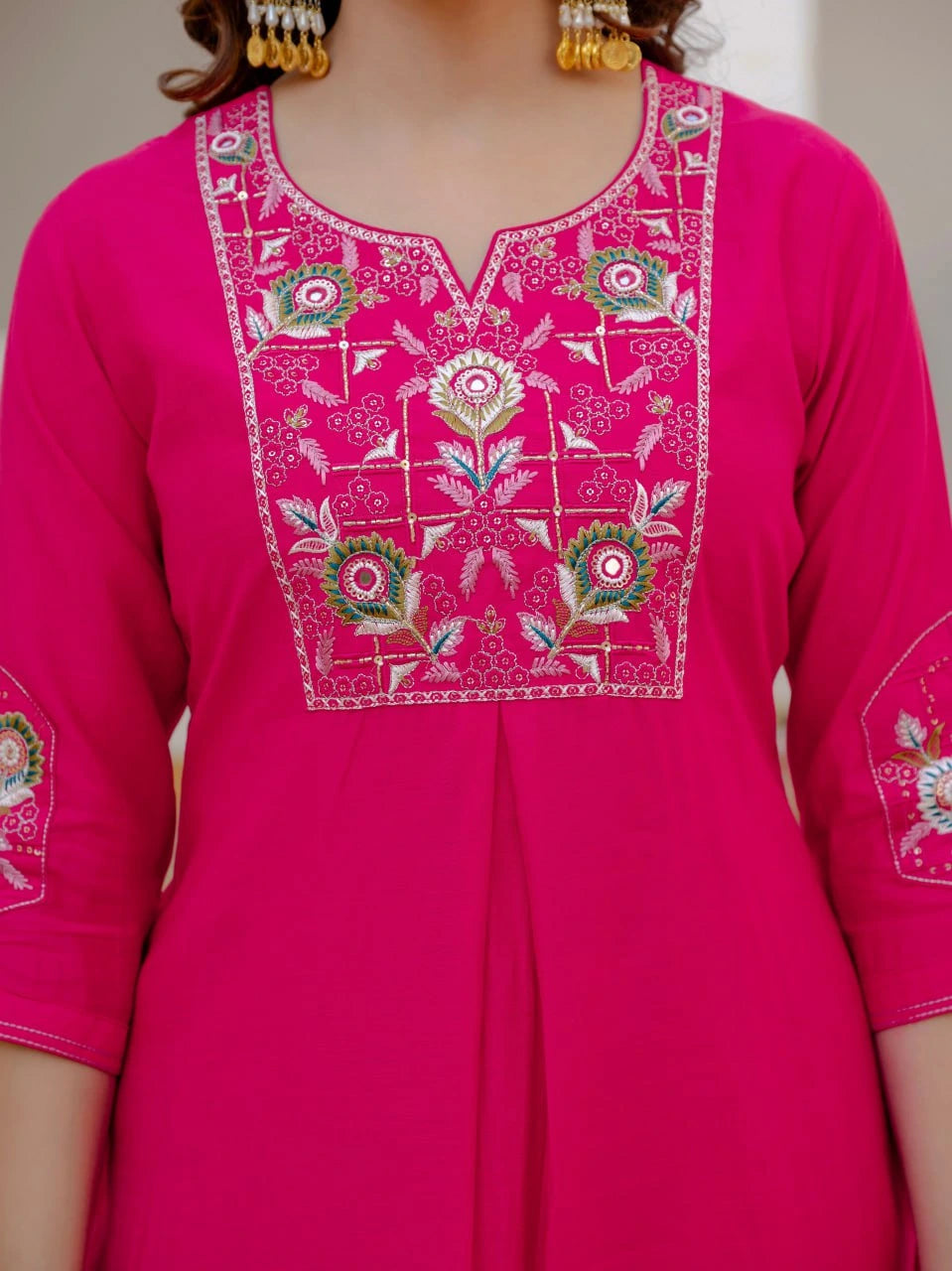 Pink embroidered dress with intricate patterns on a plain background