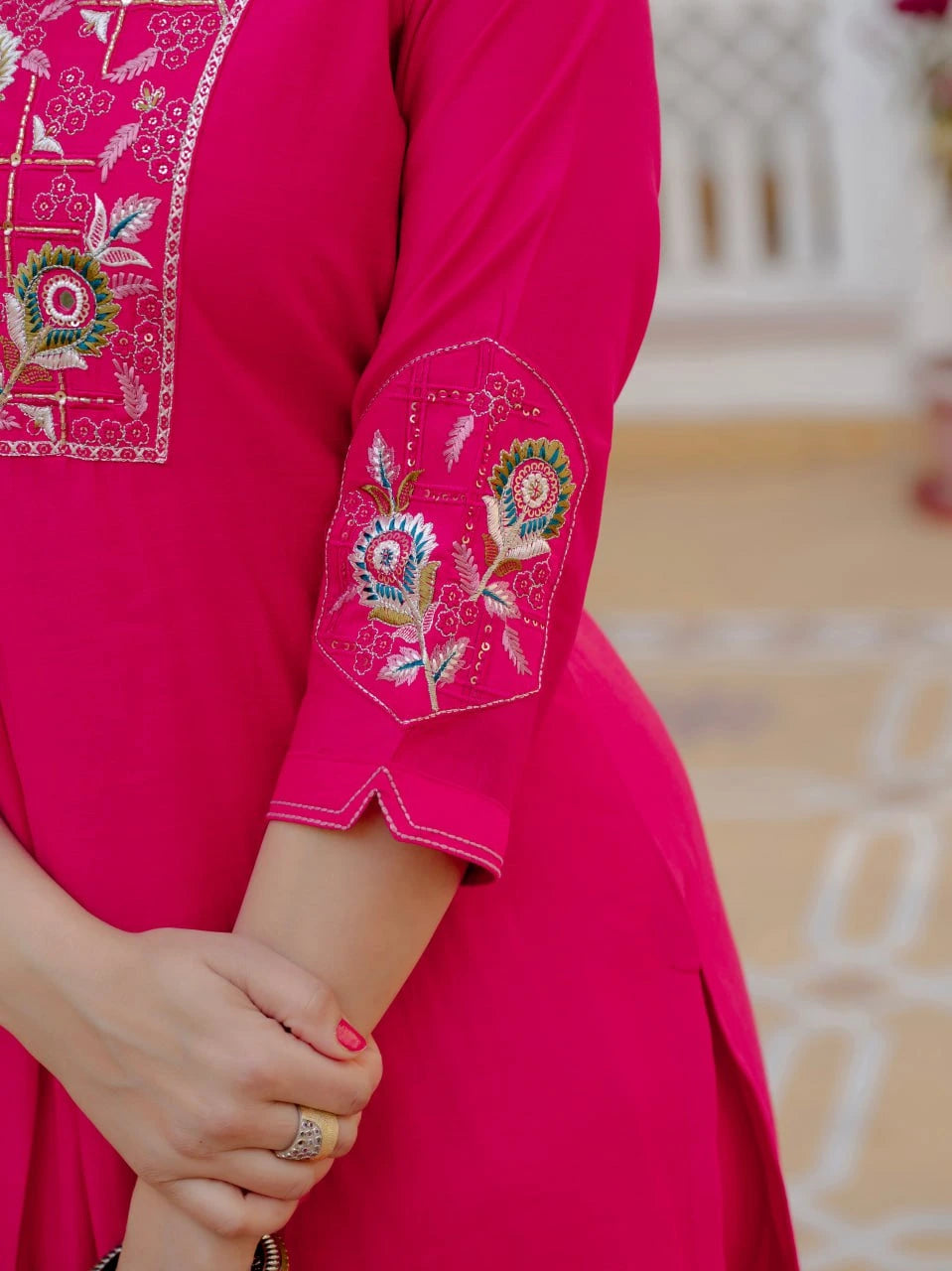Close-up of a bright pink garment with intricate embroidery on a blurred background