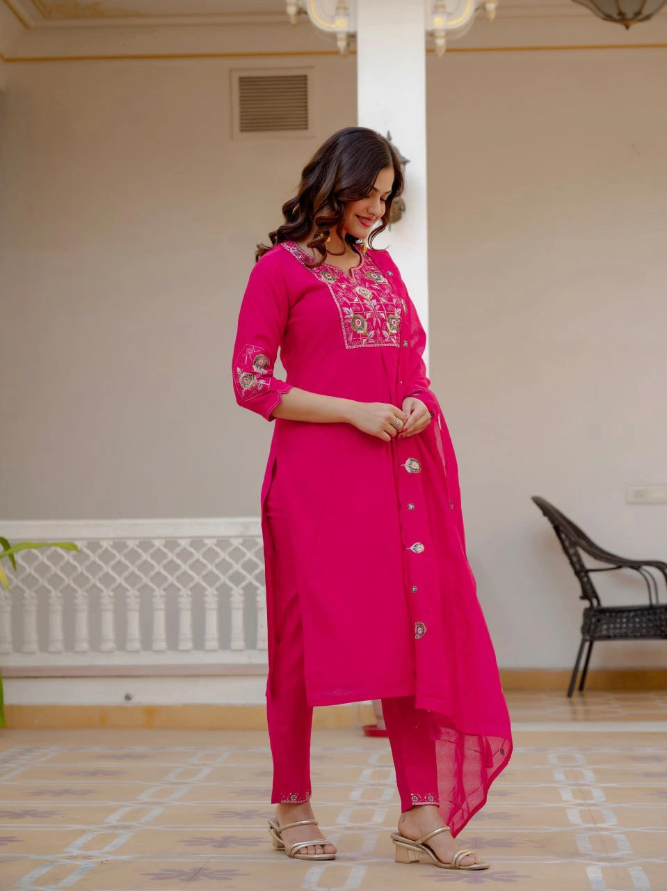 Woman wearing a pink traditional outfit with embroidery in a room.