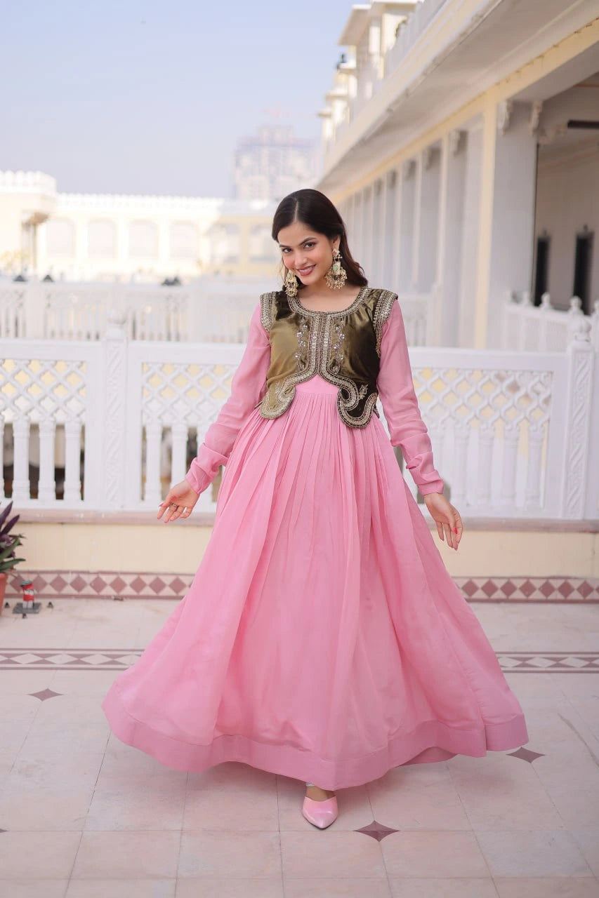 Woman in a pink traditional outfit with gold details standing on a rooftop.