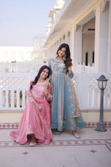Two women in traditional outfits standing on a balcony with a building in the background.