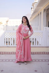 Woman in a pink traditional outfit standing on a balcony with a white building in the background