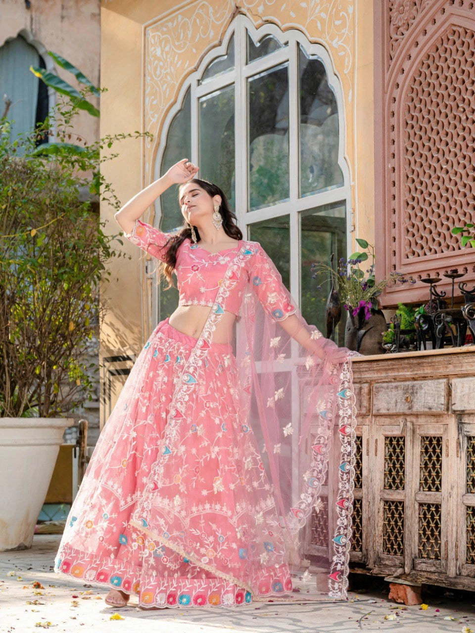 Woman in a pink traditional outfit standing in front of a decorative building.