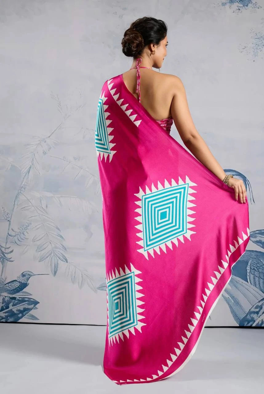 Woman wearing a bright pink saree with blue and white patterns against a light gray background