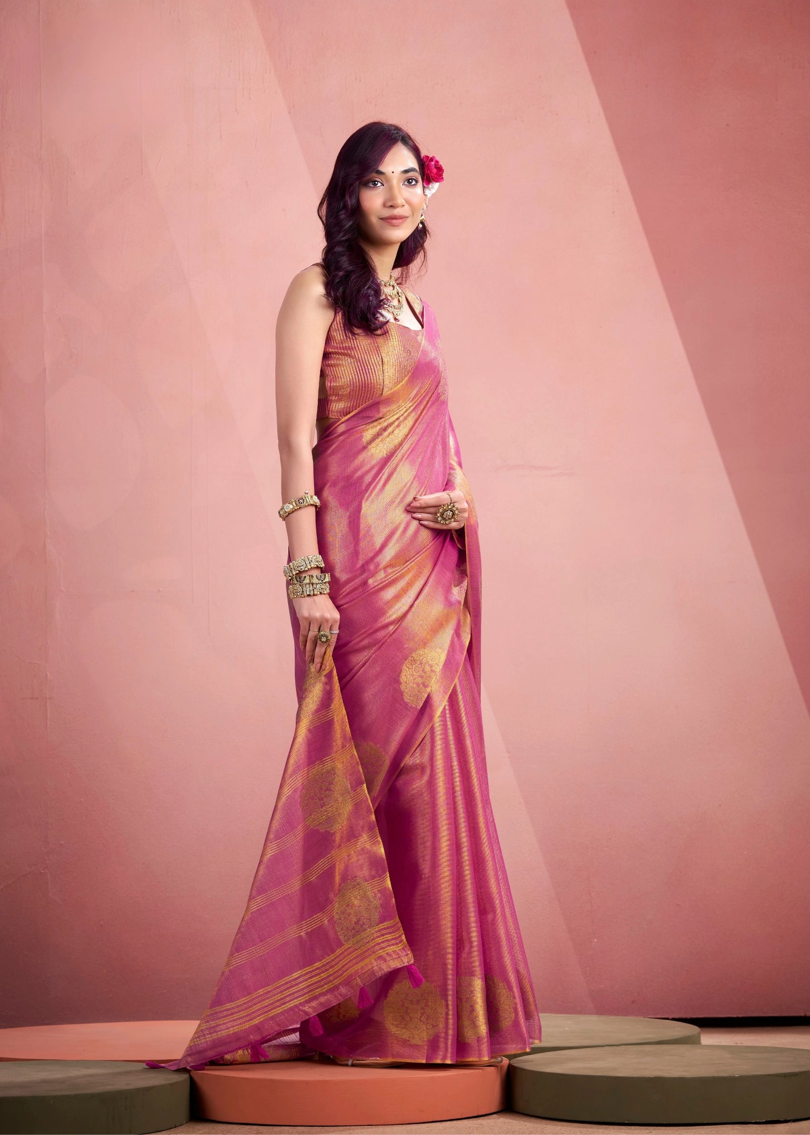Woman wearing a pink and purple saree against a neutral background