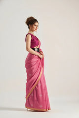 Woman wearing a pink saree with a matching blouse on a white background