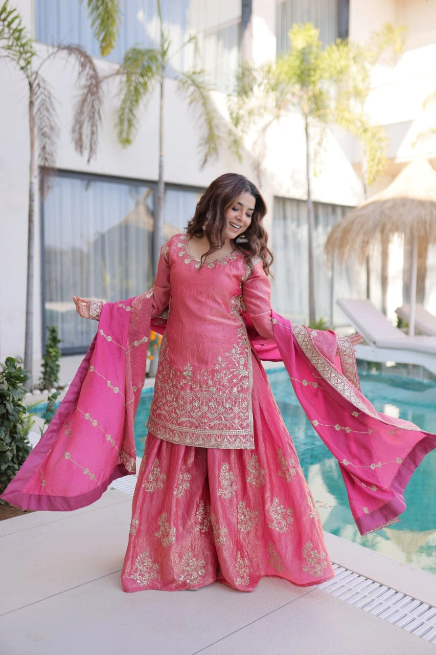 Woman in a pink traditional outfit standing by a poolside.