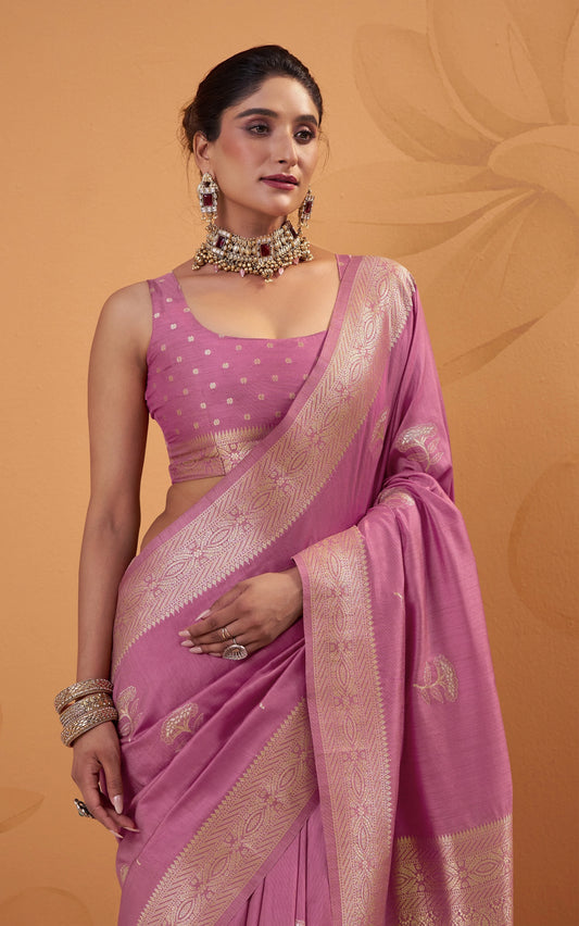 Woman wearing a pink saree with a gold border on an orange background