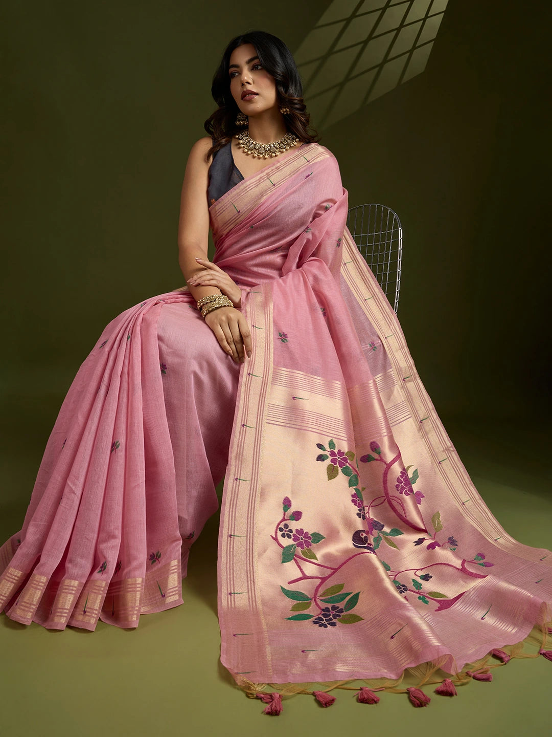 Woman wearing a pink saree with floral embroidery on a green background