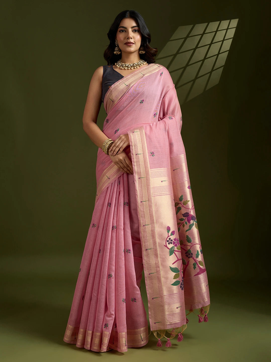Woman wearing a pink saree with floral patterns on a dark background