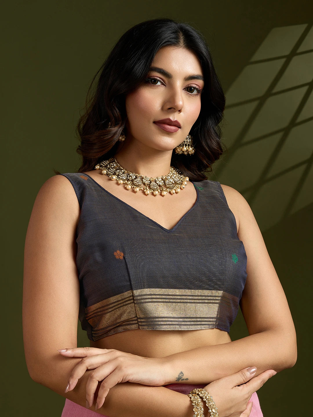 Woman wearing a traditional outfit with jewelry against a green background