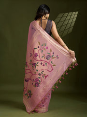 Woman holding a pink embroidered saree with floral patterns on a green background