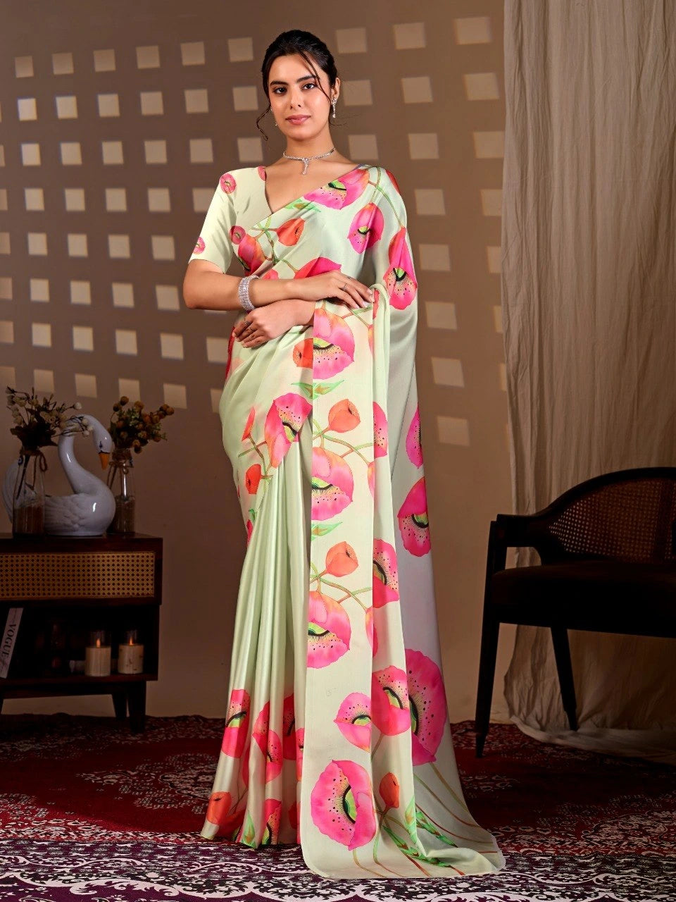 Woman wearing a light green saree with pink floral patterns in a room setting.