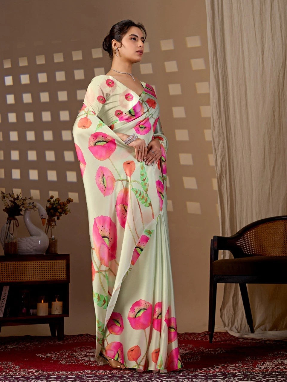 Woman wearing a floral saree in a room with a checkered wall and a chair.