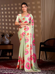 Woman wearing a light green saree with pink floral patterns in a room setting.