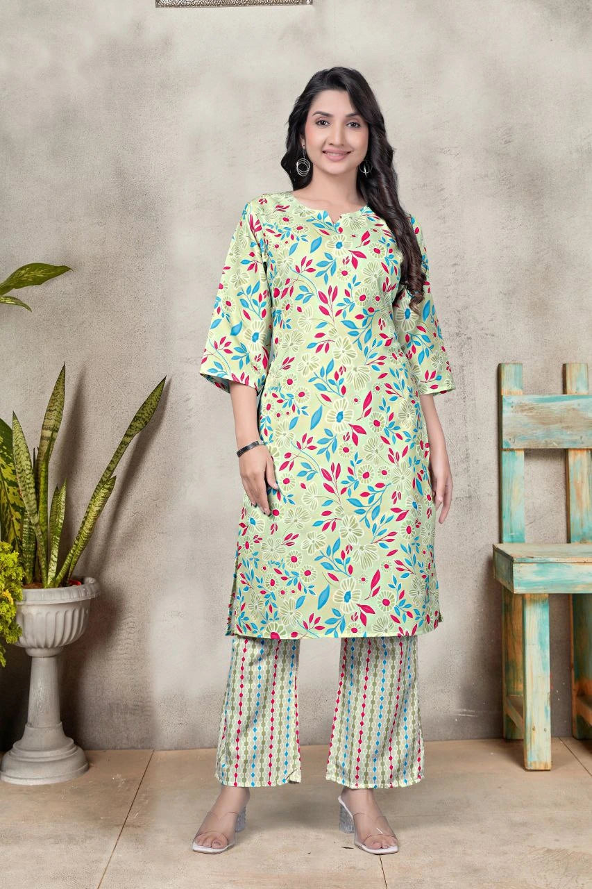 Woman wearing a floral kurta with pants standing against a textured wall.