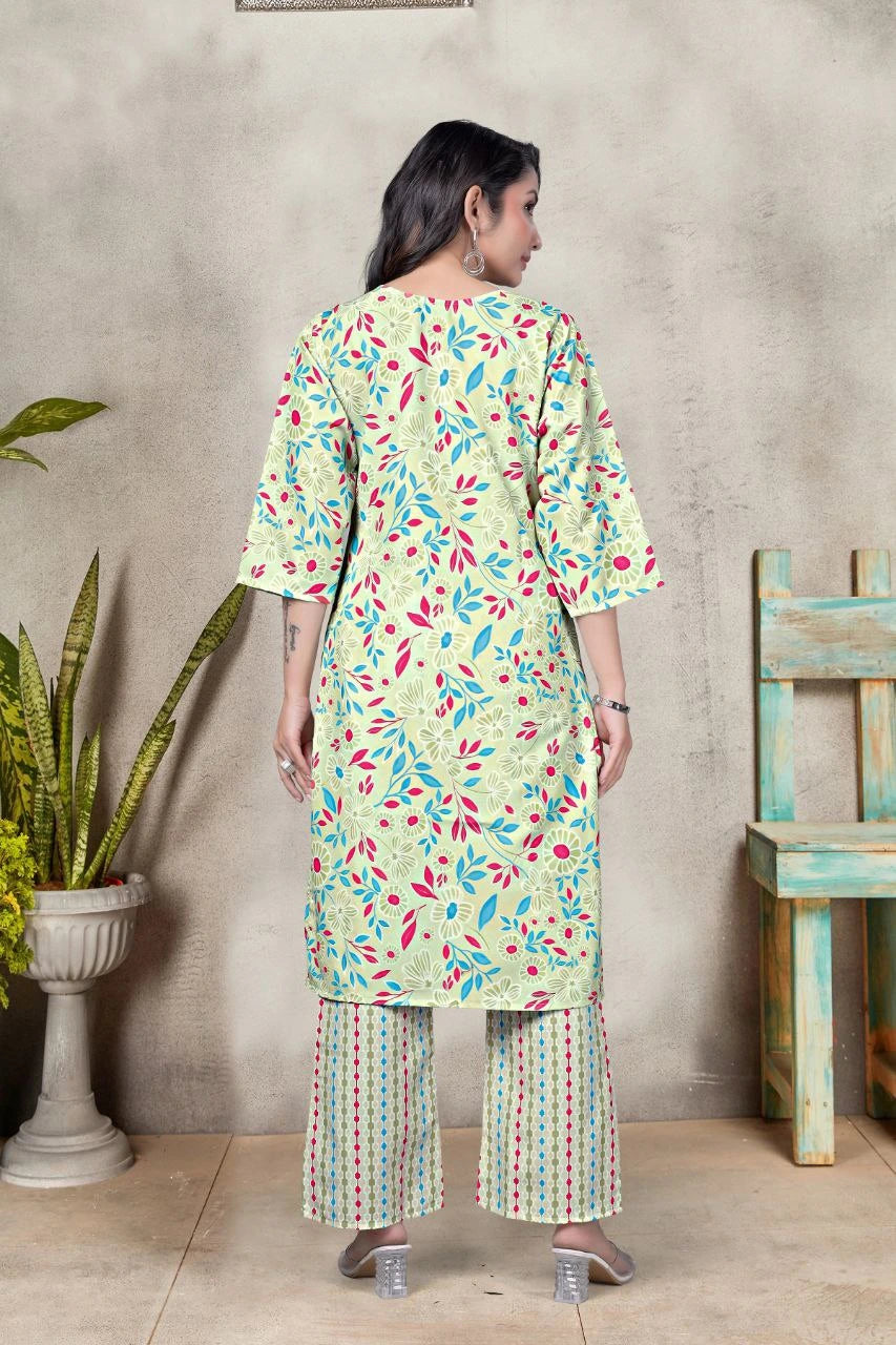 Woman wearing a light green floral printed outfit standing against a textured wall.