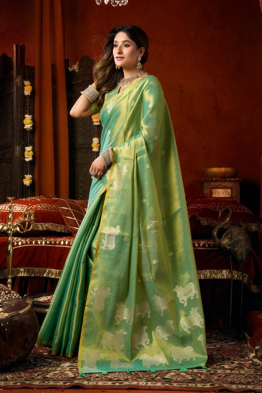 Woman in a green saree with elephant patterns in an elegant indoor setting