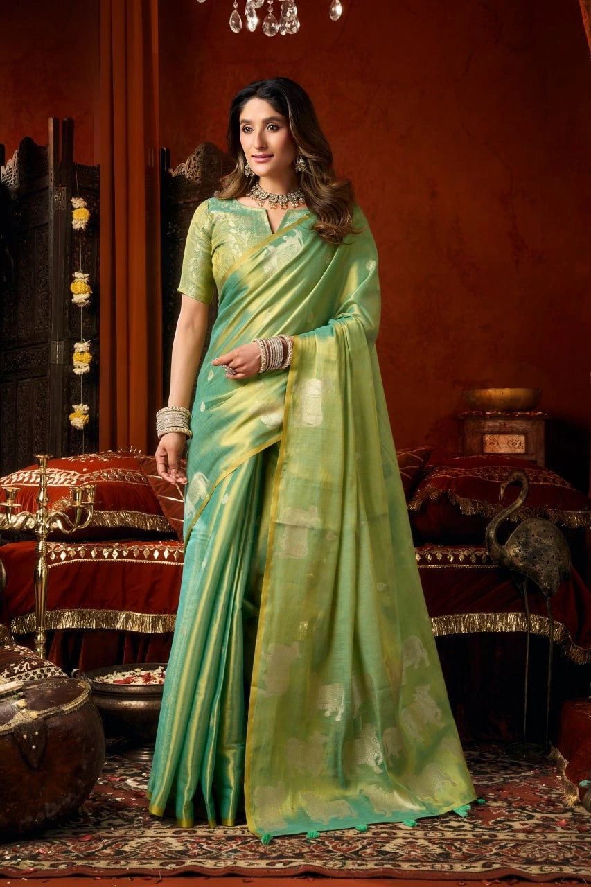 Woman in a green saree standing in an ornate room with decorative elements.