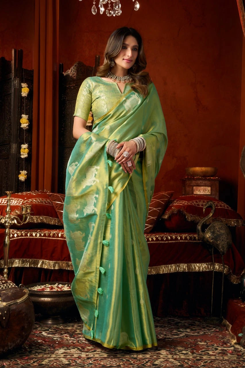 Woman in a green saree standing in an ornate room with red walls and decorative elements.