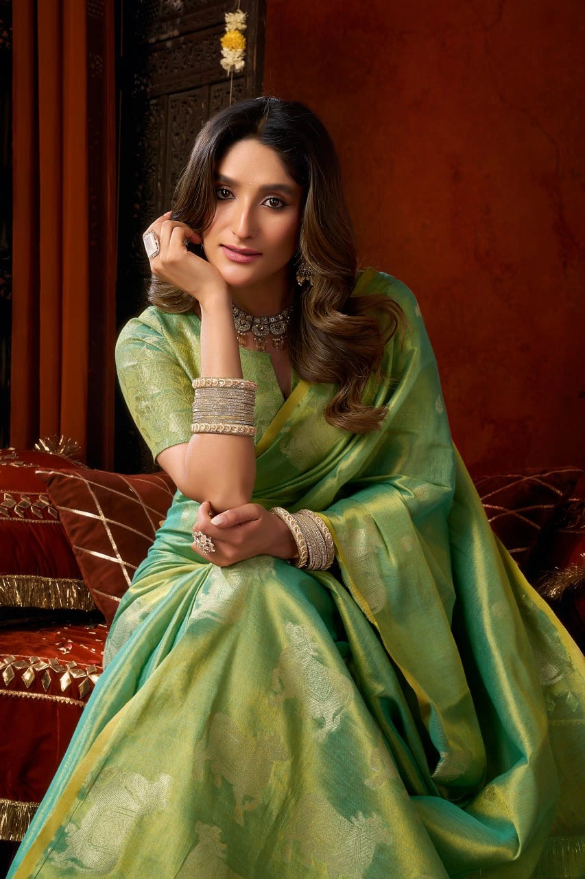 Woman in a green saree with jewelry against a warm-toned background