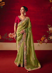 Woman wearing a green saree with a red blouse against a decorative red background
