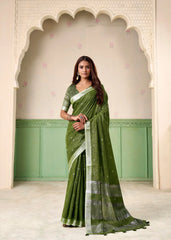 Woman wearing a green saree with a white border in front of an archway.