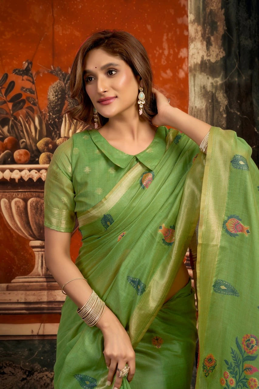 Woman wearing a green saree with floral patterns in an indoor setting.