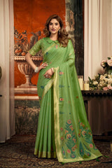 Woman wearing a green saree with floral patterns indoors.