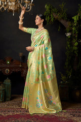 Woman in a light green saree with floral patterns in a decorative setting.