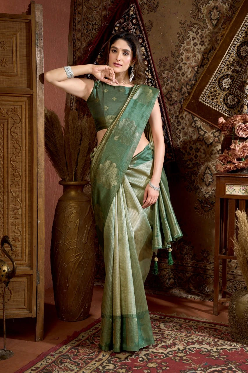 Woman in a green saree standing in an ornate room with decorative elements.