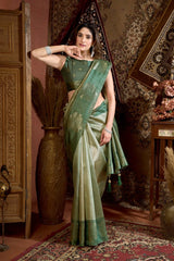 Woman in a green saree standing in an ornate room with decorative elements.