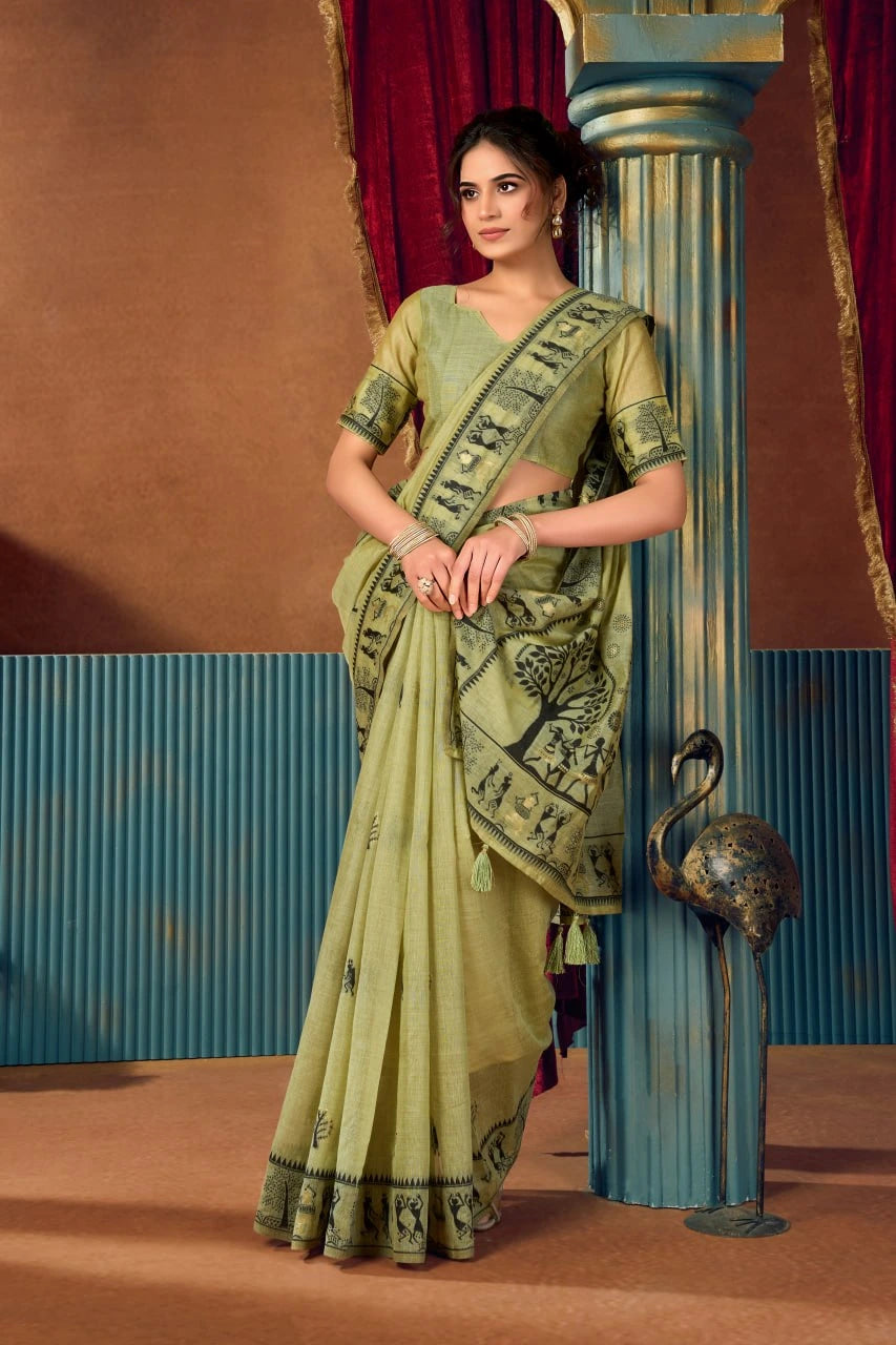 Woman in a green saree standing next to a decorative column with a red curtain background