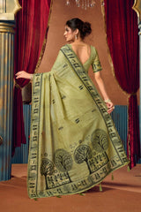 Woman wearing a green saree with black patterns in a decorative setting