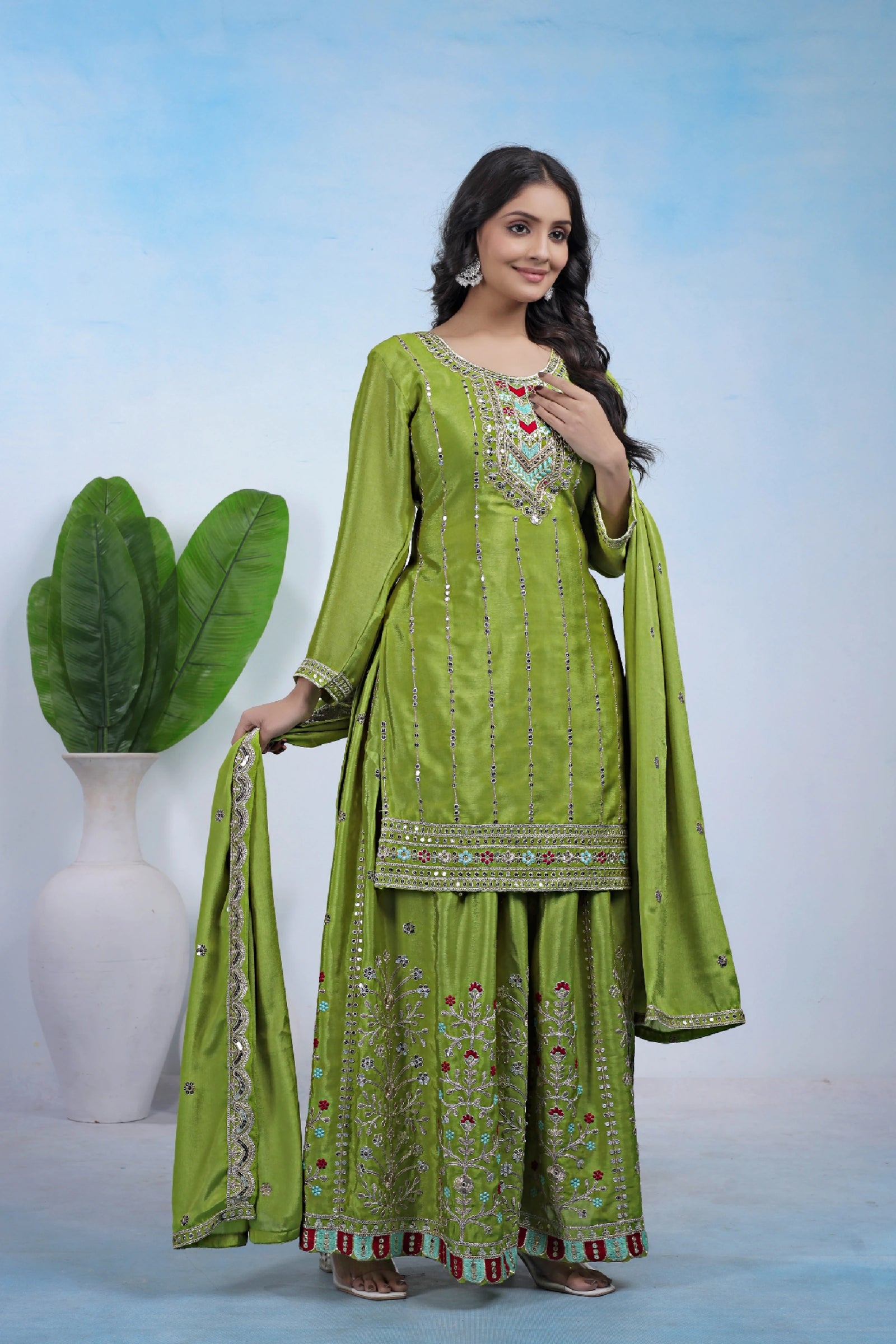 Woman wearing a green embroidered traditional outfit with a white background