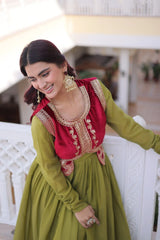 Woman in a red and green traditional outfit with gold embroidery, sitting on a white bench.