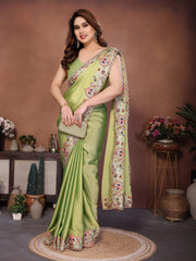 Woman wearing a green saree with floral patterns in a decorated room.